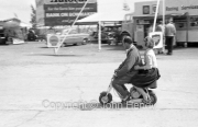 Stirling Moss on a scooter in the paddock